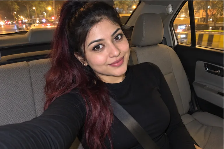 A woman in a black dress takes a selfie in the back seat of a cab at night, on her way to the booking