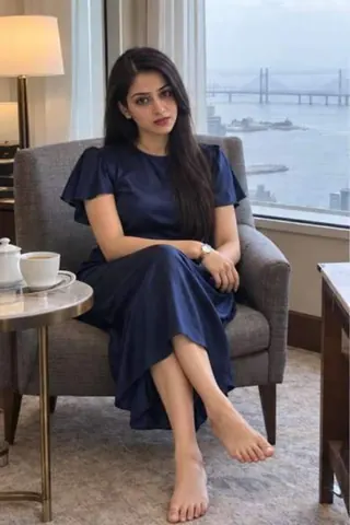 Madhu, 26, call girl in Worli, Mumbai: in an armchair by a hotel window with the Sea Link behind her, in a navy dress