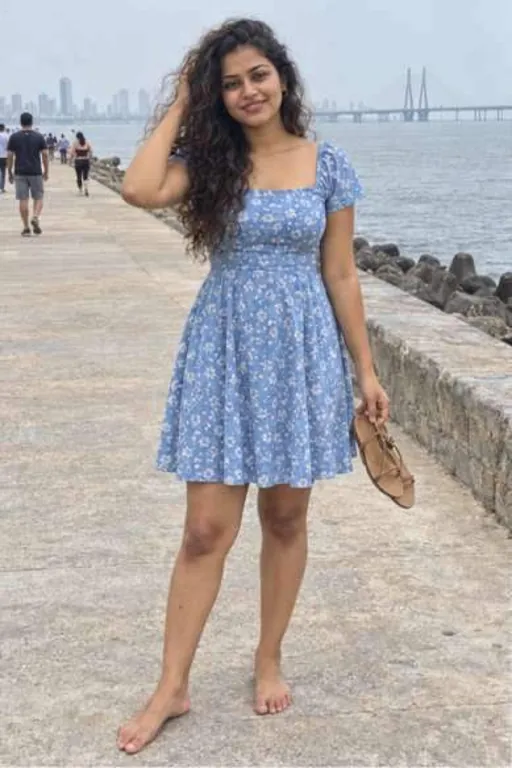 Meera, 24, call girl in Bandra, Mumbai: barefoot on the Bandra sea wall in a blue floral dress, sandals in her hand
