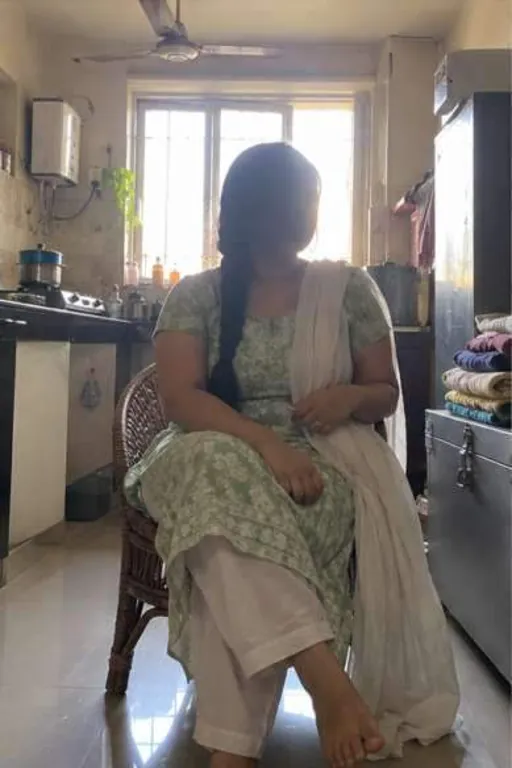 Nisha, 26, call girl in Andheri, Mumbai: at home by a bright window in a green salwar suit, her face in shadow